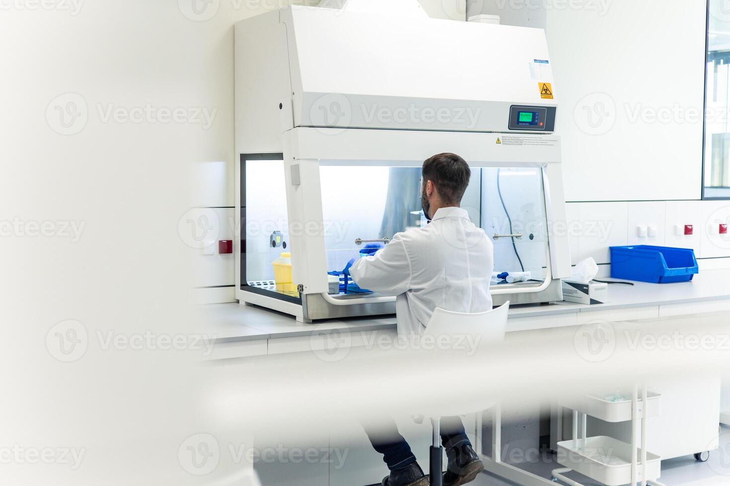 Scientist working with sterile cabinet in laboratory performing experiment photo