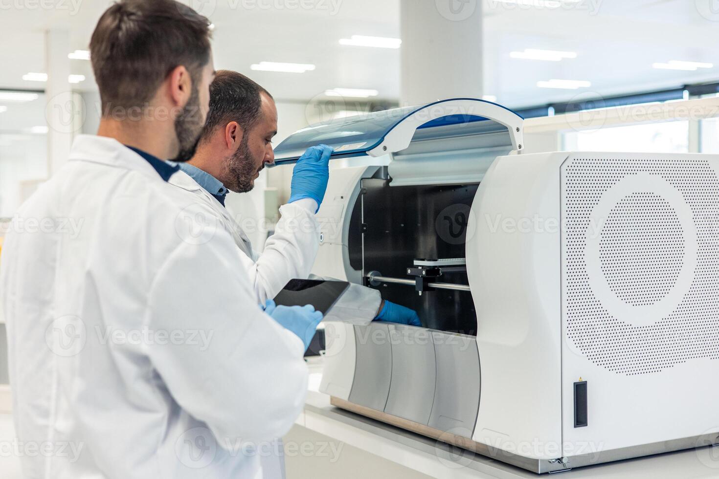 Laboratory technicians working with modern automated equipment in medical lab photo