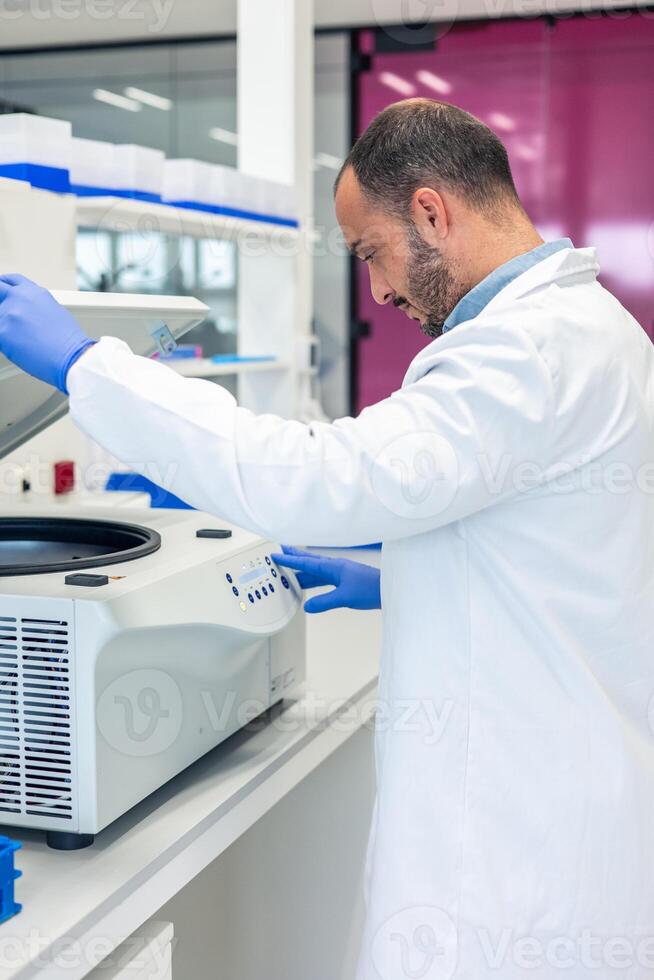 Scientist using laboratory centrifuge for research in modern laboratory photo