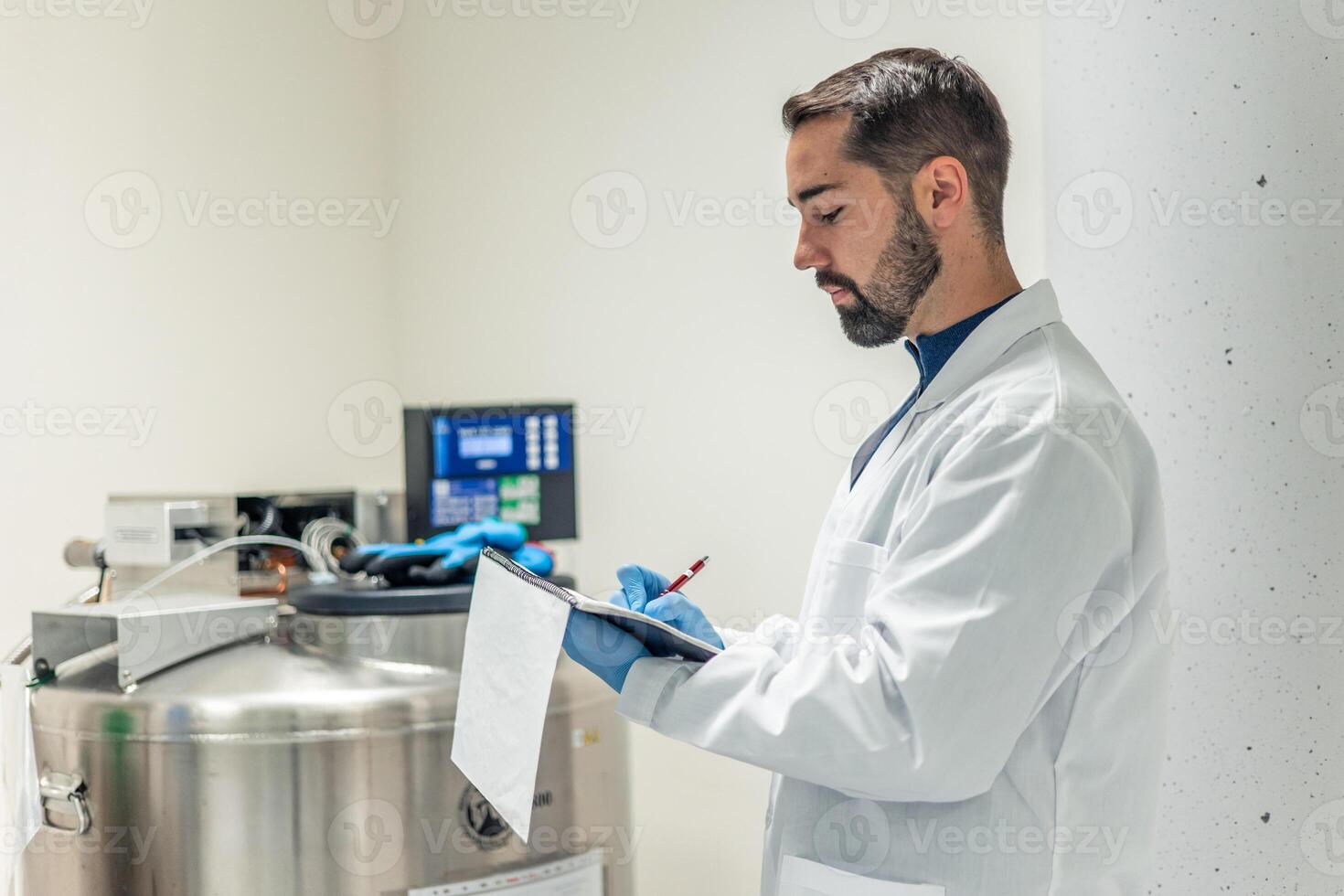 Scientist taking notes on clipboard in laboratory with cryogenic equipment photo