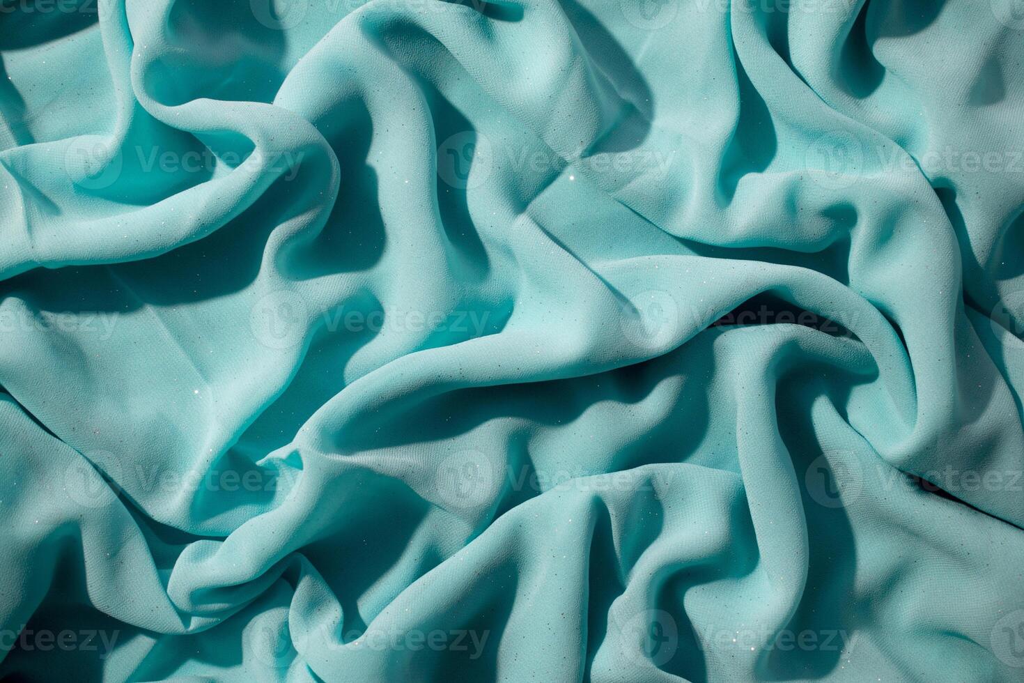 Turquoise wavy crumpled fabric with little sparkling dust, fabric texture and background. photo