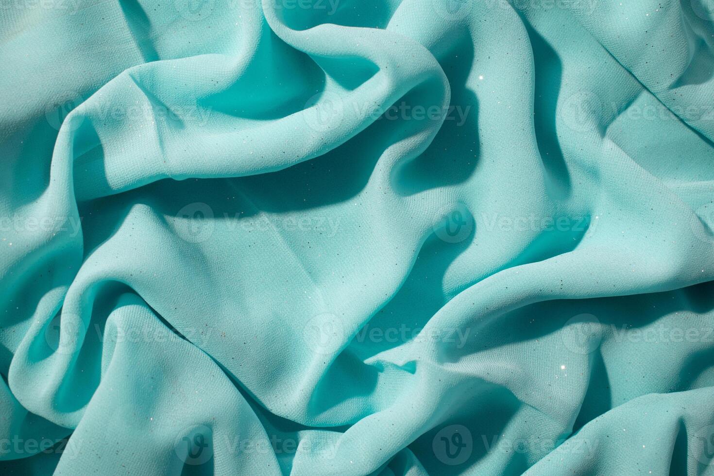 Turquoise wavy crumpled fabric with little sparkling dust, texture and abstract background. photo