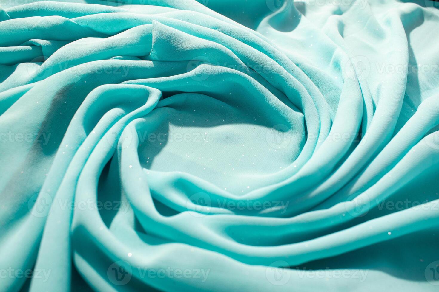 Spiral Twisted Turquoise wavy fabric with little sparkling dust and copy space in center, texture and background. photo