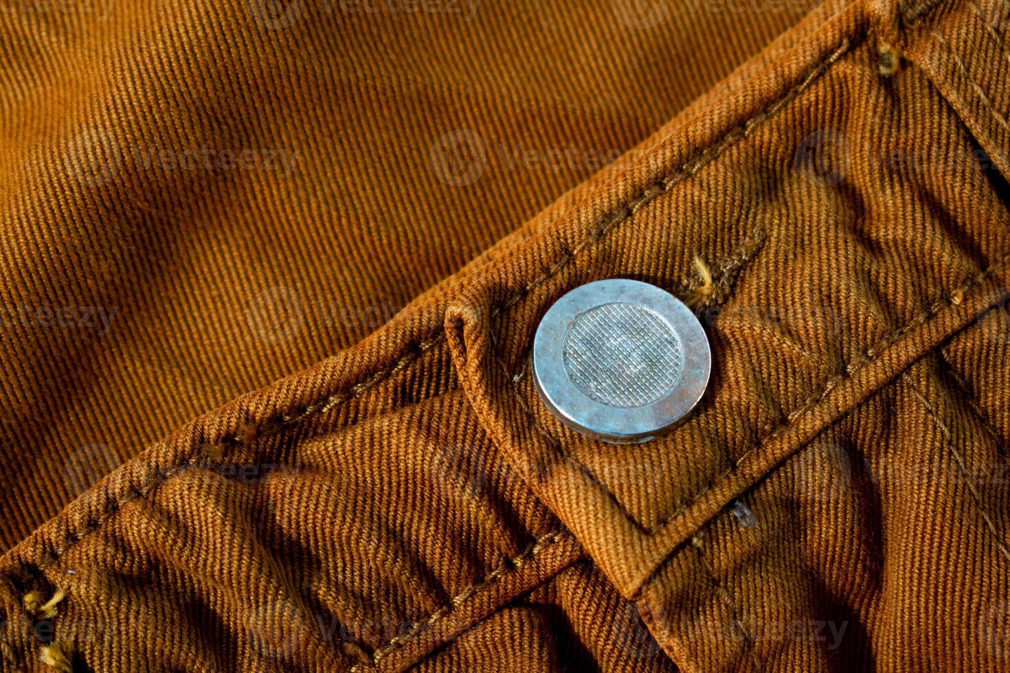 Metallic button on bright brown jeans, fabric texture mockup background photo