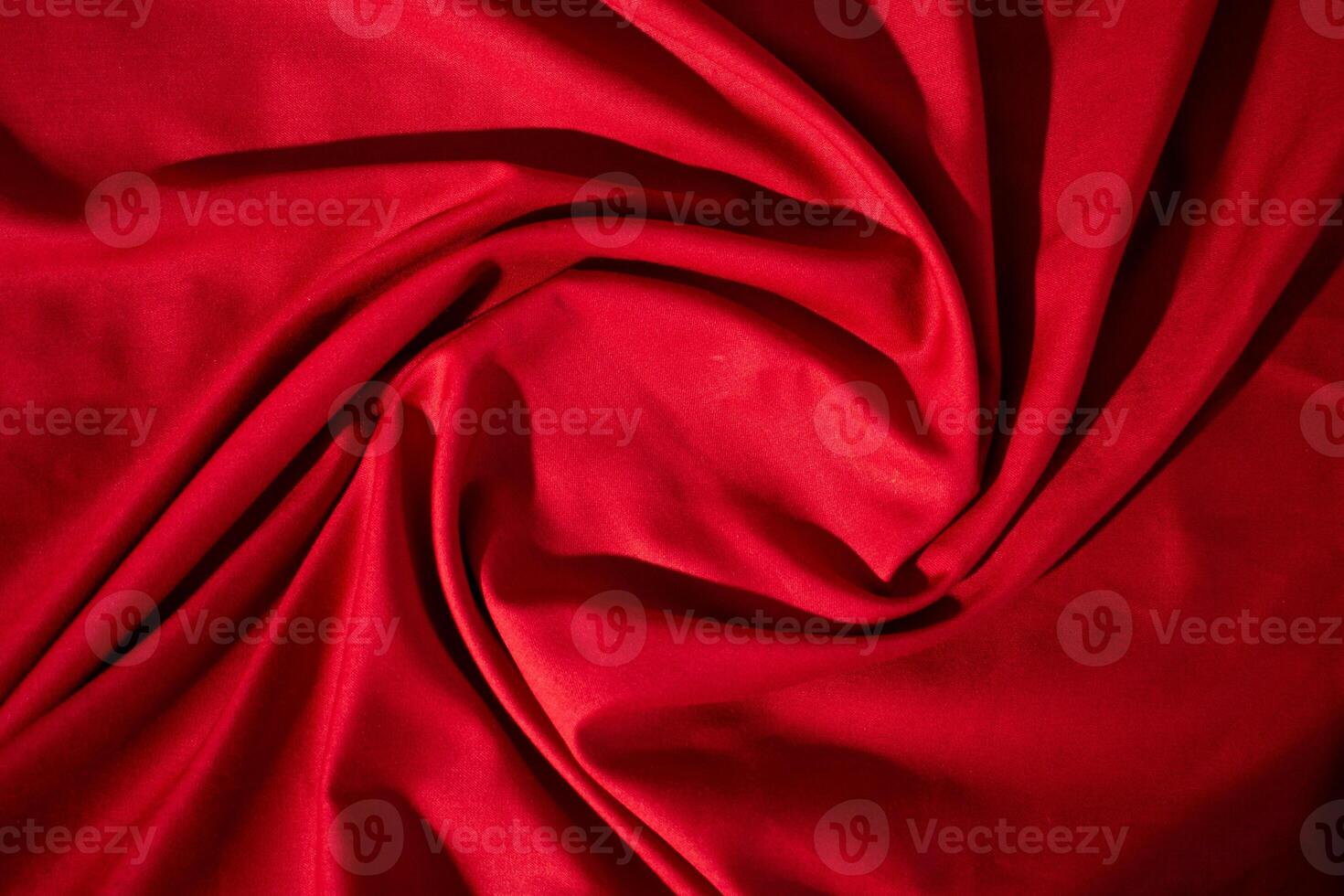 Red fabric wavy spiral crumpled texture with copy space in the center. photo