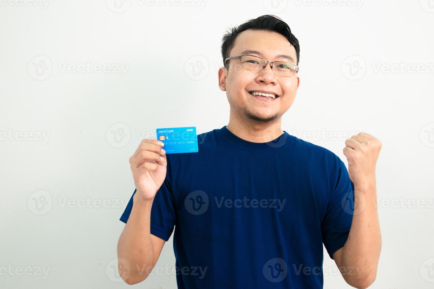 cheerful asian man Celebrating pose with hold credit card. Banking, Financial concept with fist up gesture. Blue color concept photo