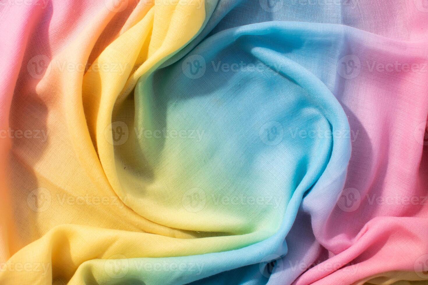Gradient yellow blue pink and green fabric wavy spiral crumpled background texture with copy space. photo