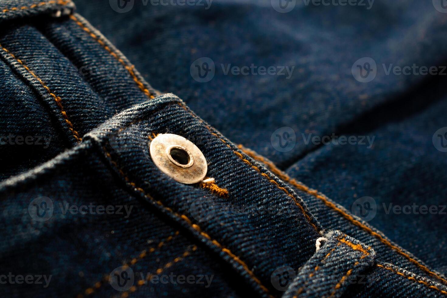 Close up gold and shiny button navy blue jeans fabric texture. photo
