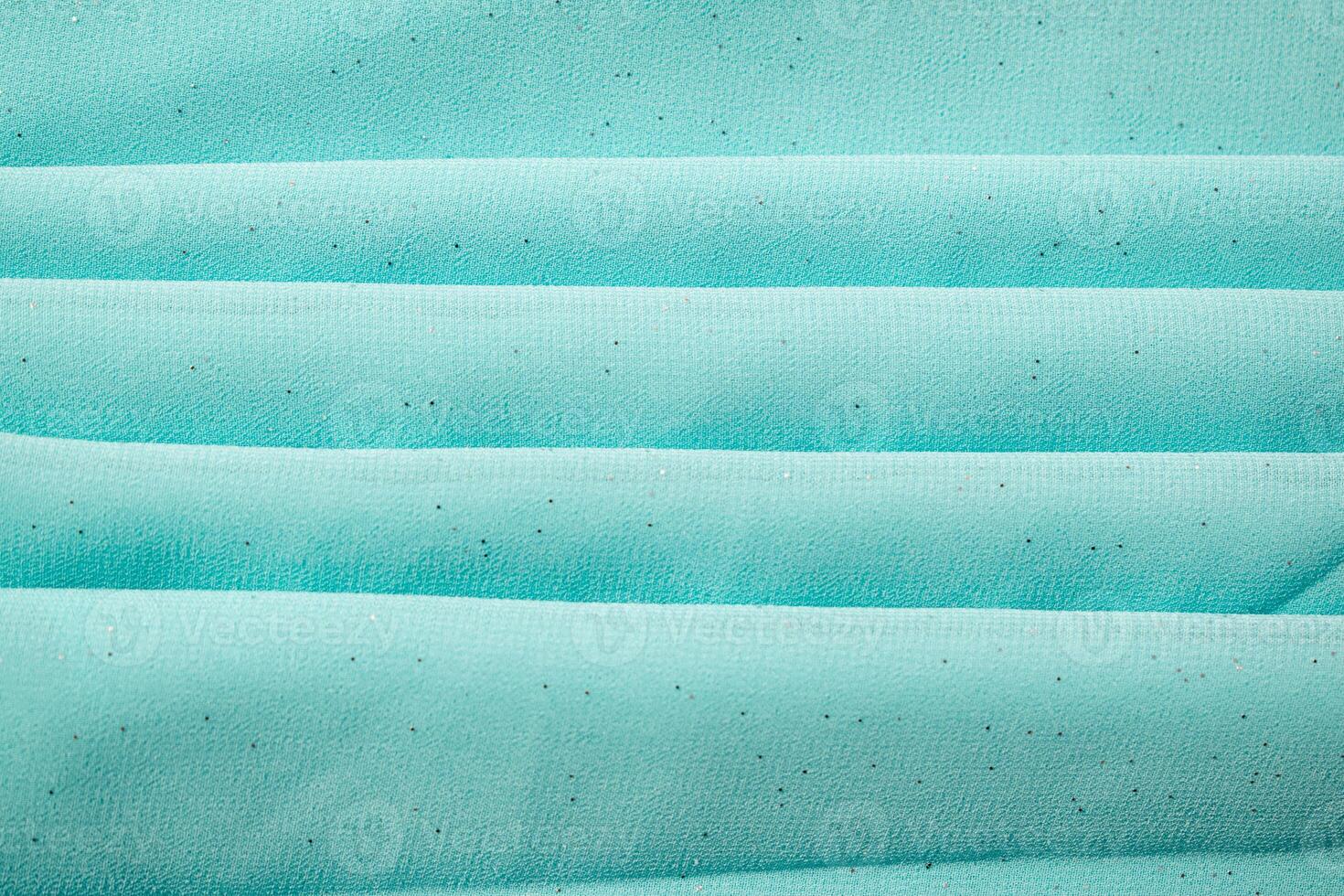 Folded Turquoise wavy crumpled fabric with little sparkling dust, texture and background. photo