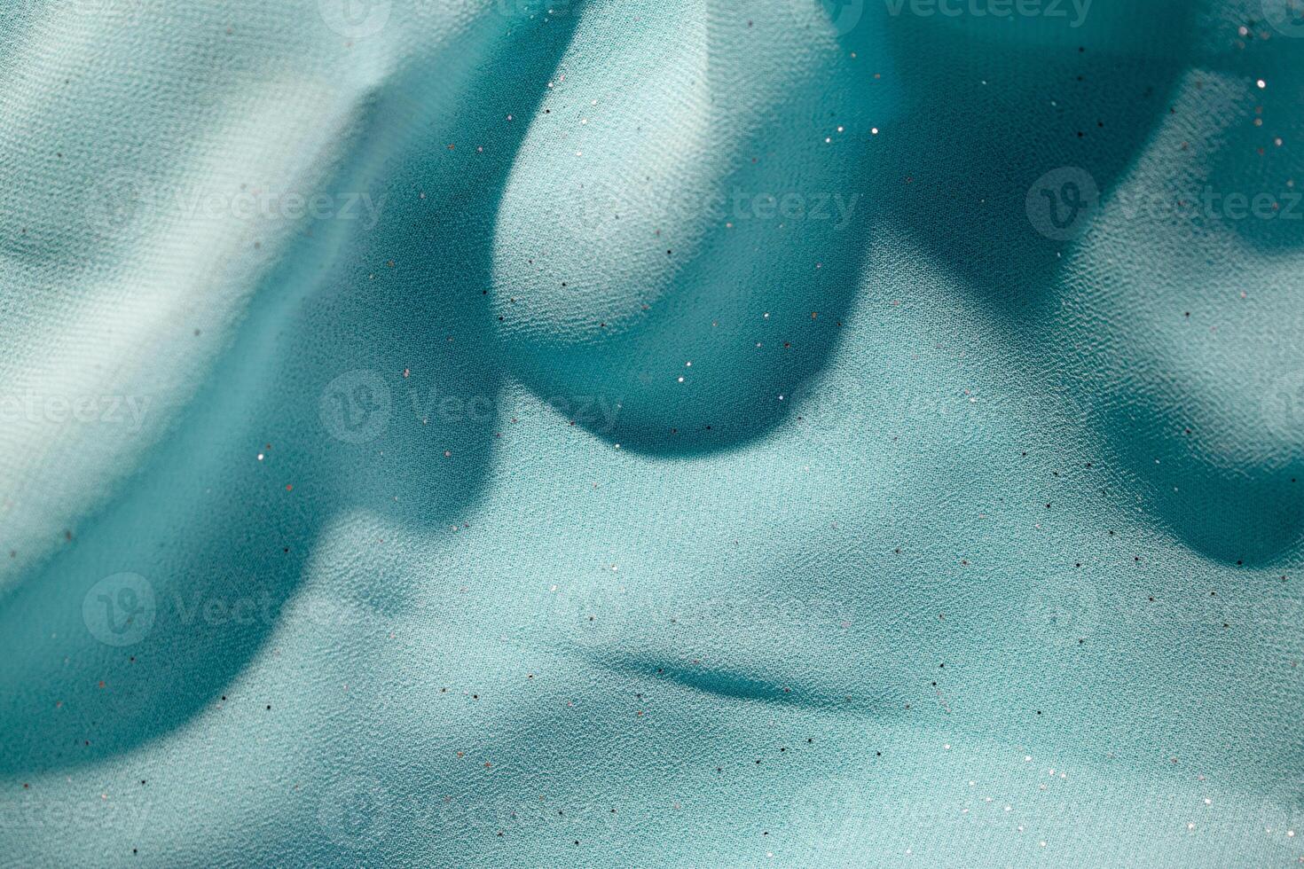Close up Turquoise wavy crumpled fabric with little sparkling dust, texture and background. photo
