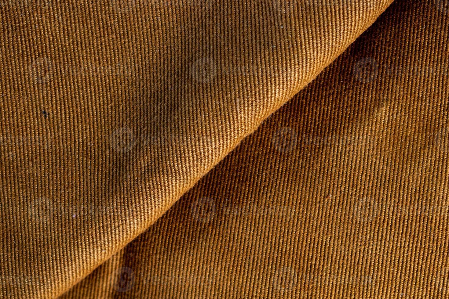 Close up detail folded bright brown jeans fabric background texture. photo