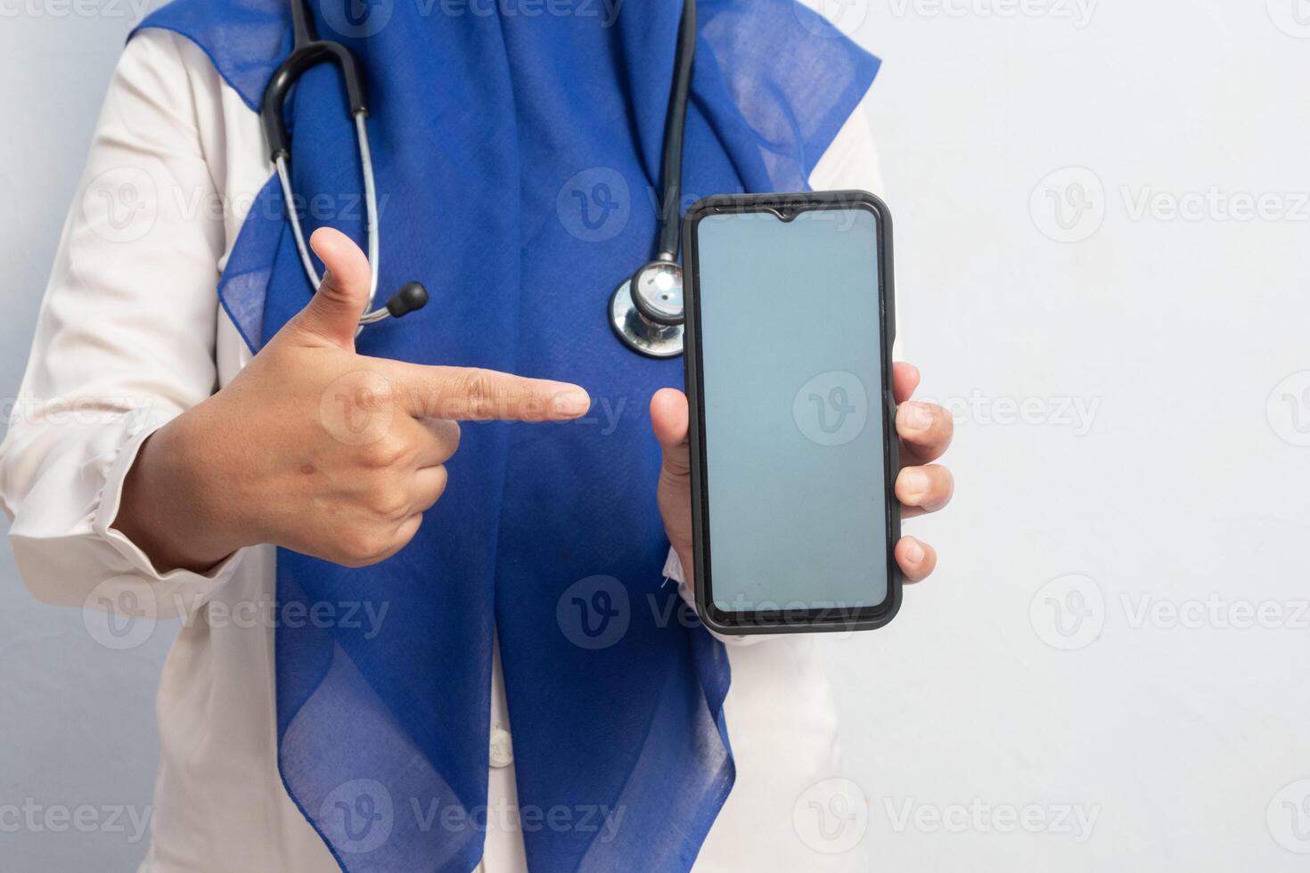 Muslim Female asian doctor or nurse holding phone and presenting hand pose. Isolated background. Medical, healthcare and nurse concept. photo