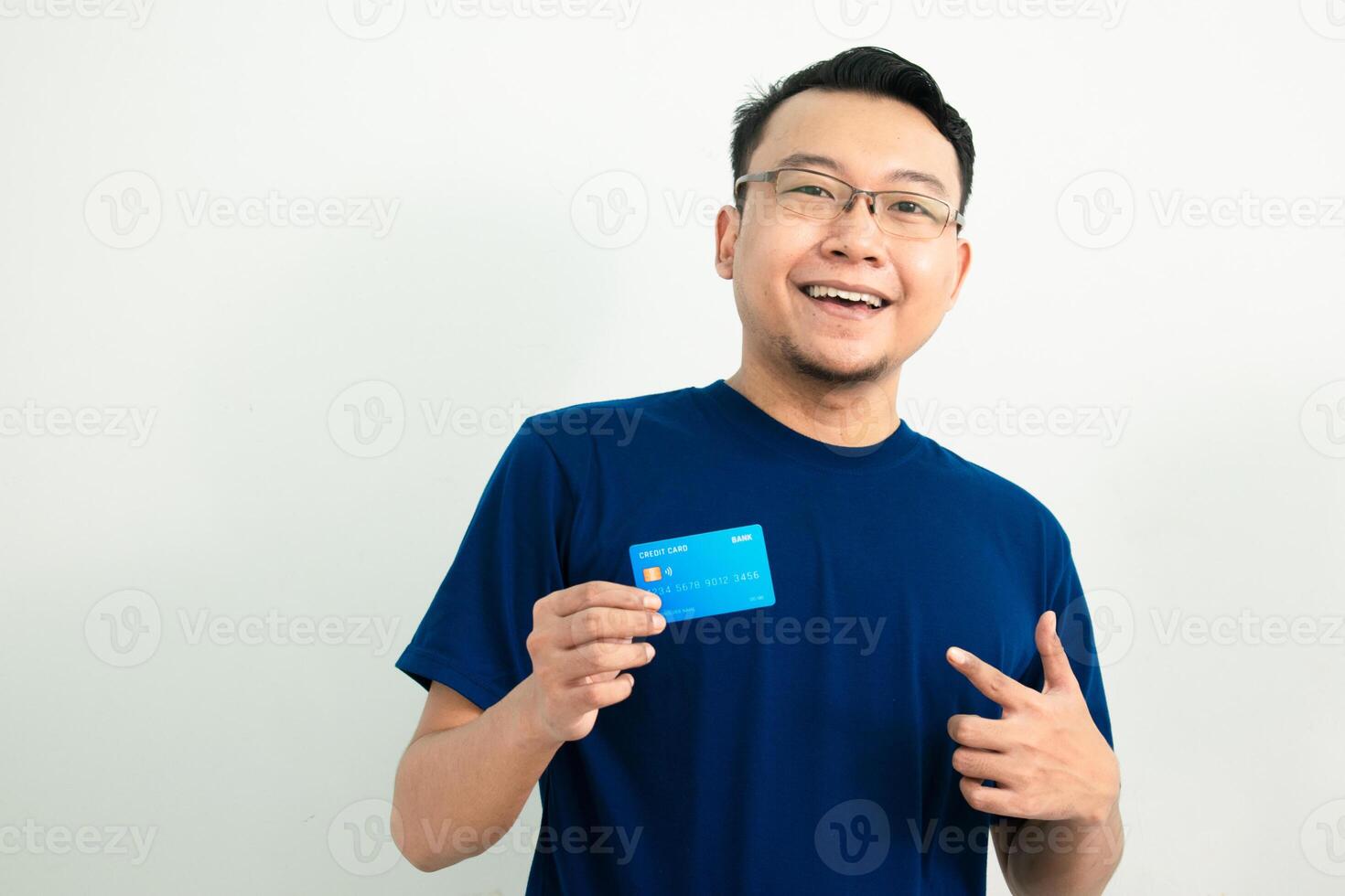 Delighted asian man hold and pointing credit card. Banking, Financial isolated background, blue color concept. photo