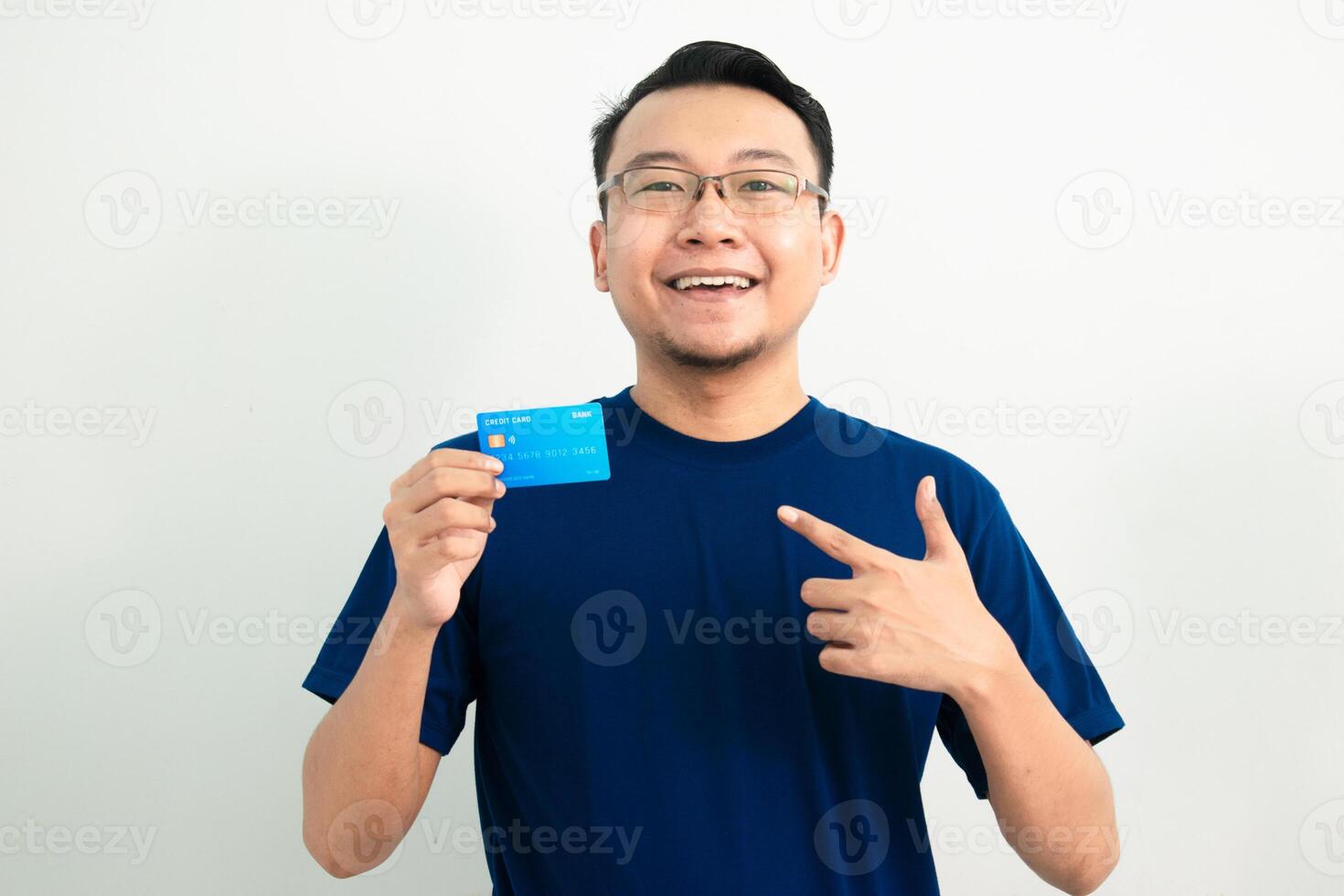Smiling asian man hold and pointing credit card. Banking, Financial isolated background, blue color concept. photo