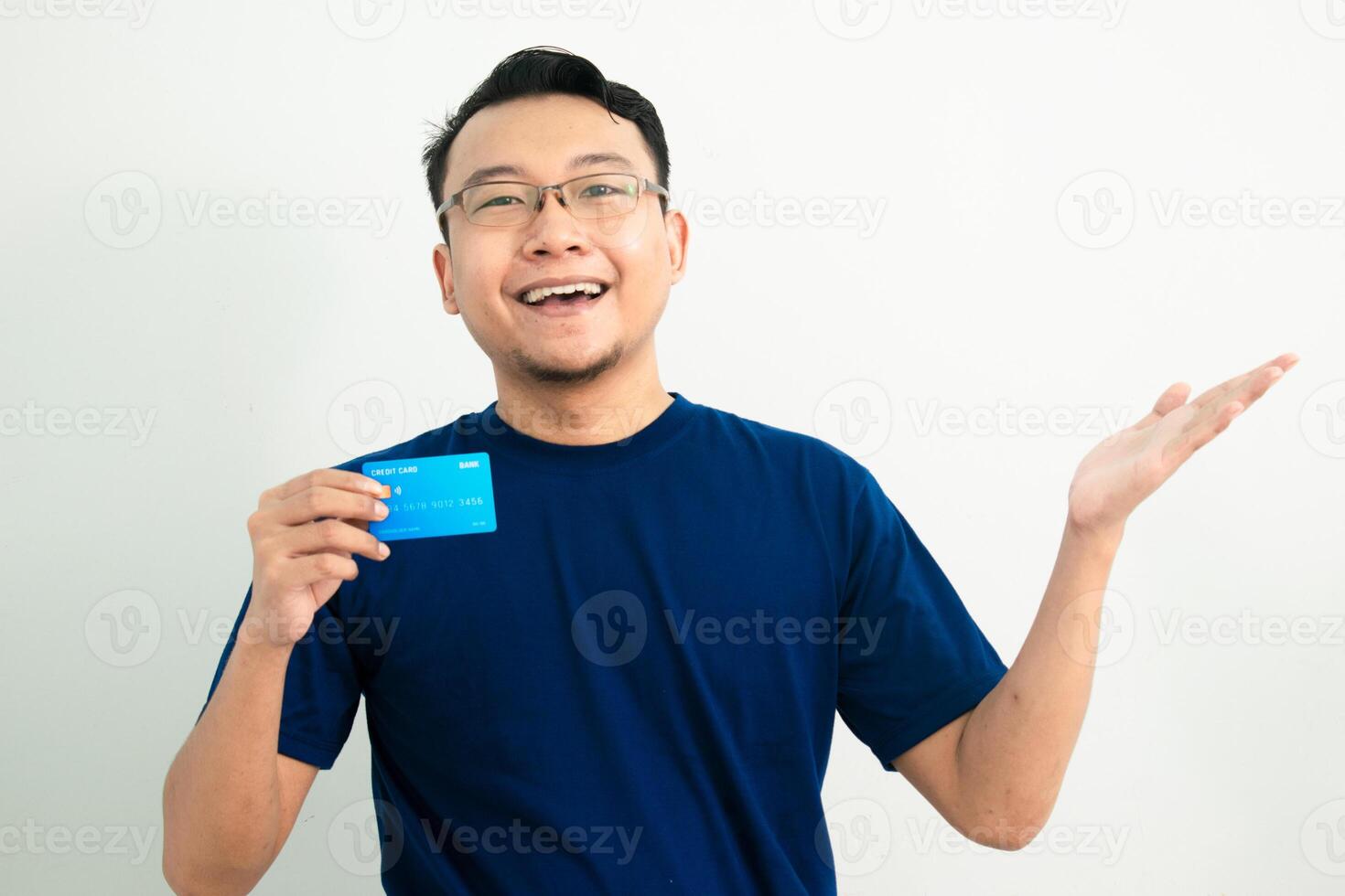 Happy asian man hold credit card and showing gesture. Banking, Financial isolated background, blue color concept. photo