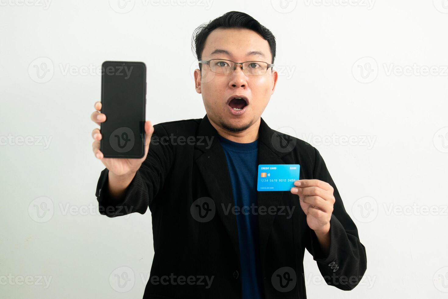 Shocked Asian businessman doing transaction with credit card and phone. Banking, Financial and technology isolated concept. photo