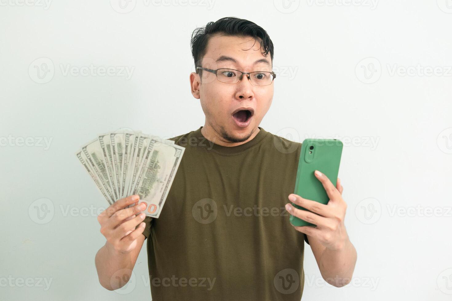 Surprised asian man hold Money and phone. Banking, Financial and technology isolated white background photo