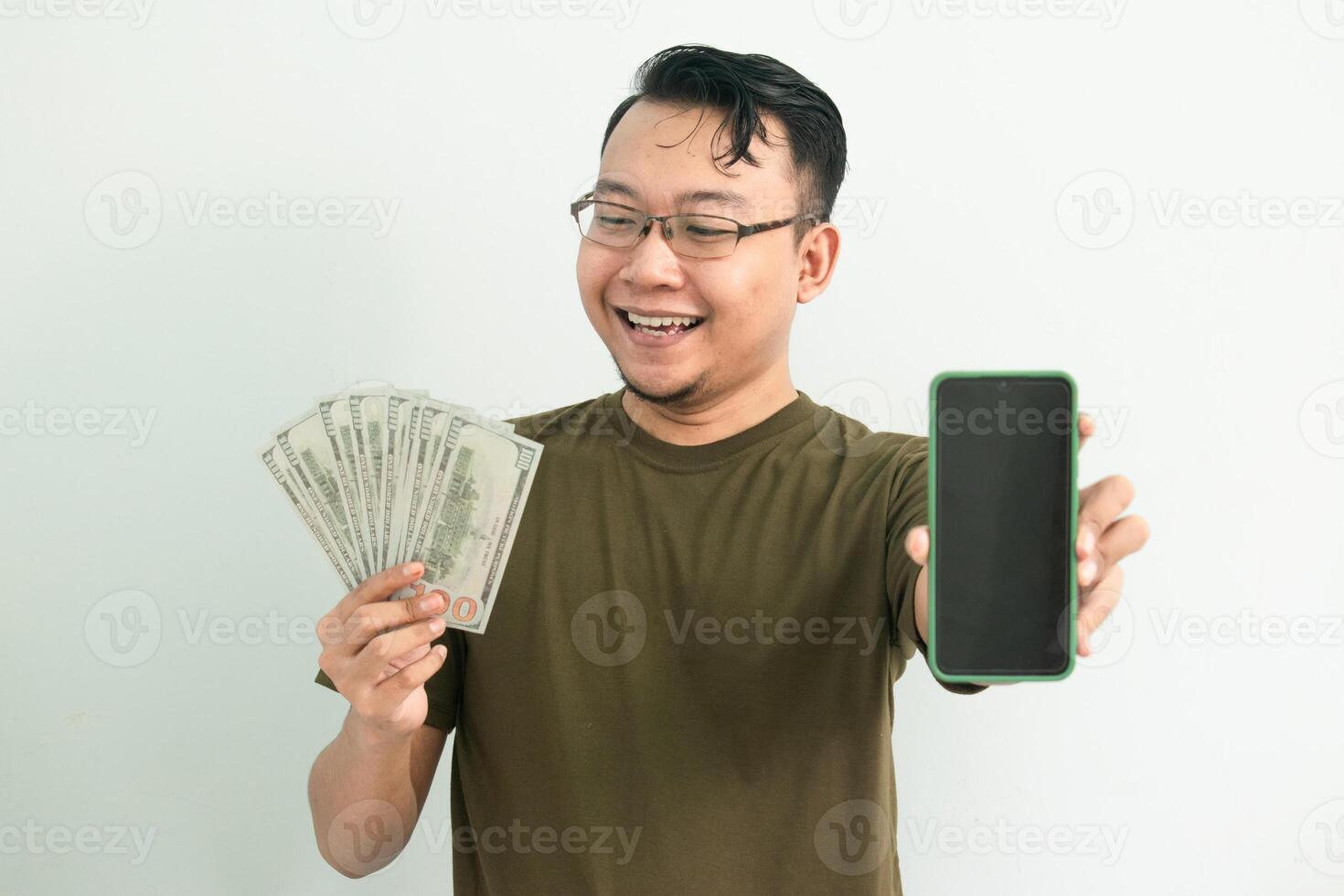 Cheerful asian man hold Money and showing phone screen. Banking, Financial and technology isolated background, green color concept. photo