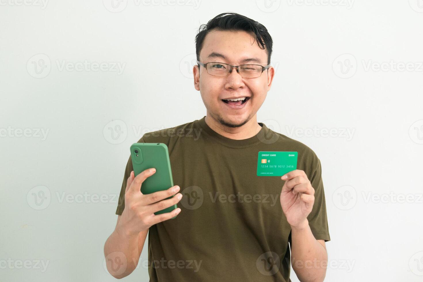 Blinked asian man wear green tshirt hold credit card and phone. Banking, Financial and technology isolated white background photo
