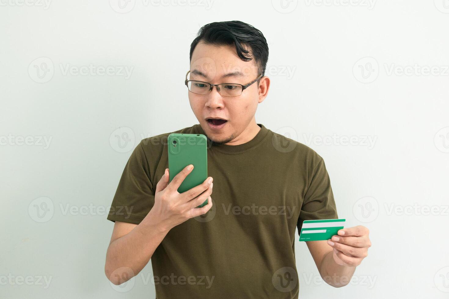 Surprised Asian man doing transaction with credit card and phone. Banking, Financial and technology isolated background, green color concept. photo