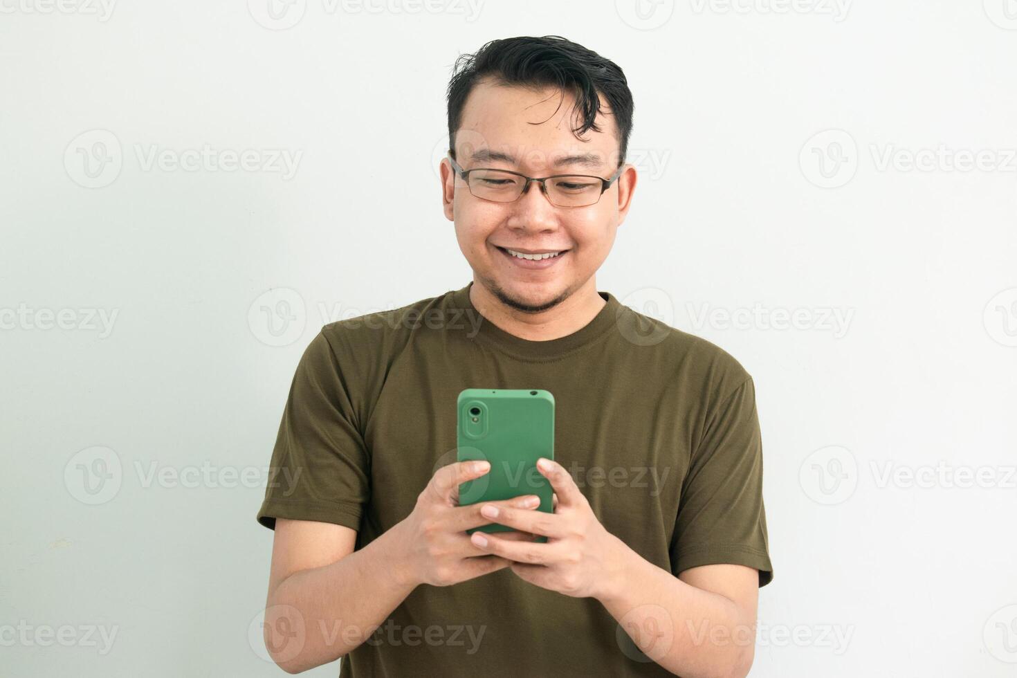 Smiling Asian man looking at phone. portrait isolated background, green color concept. photo