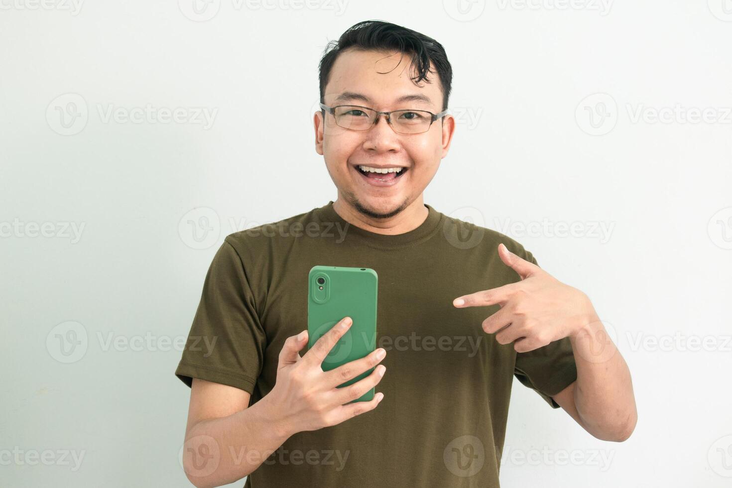 Joyful Asian man pointing at phone. portrait isolated background, green color concept. photo