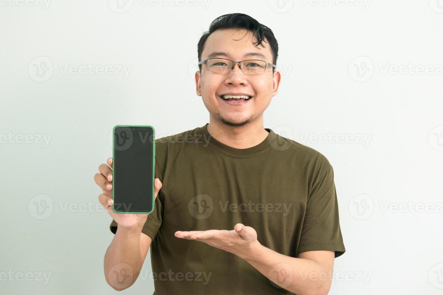 Joyful Asian man wear green tshirt pointing at phone. portrait isolated background, green color concept. photo