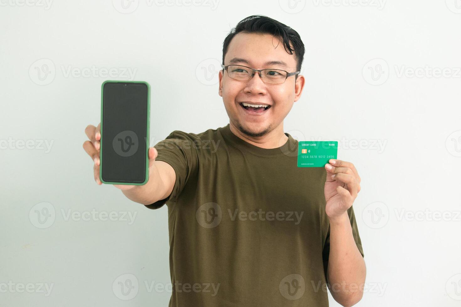 Happy asian man wear green tshirt hold credit card and phone. Banking, Financial and technology isolated background photo