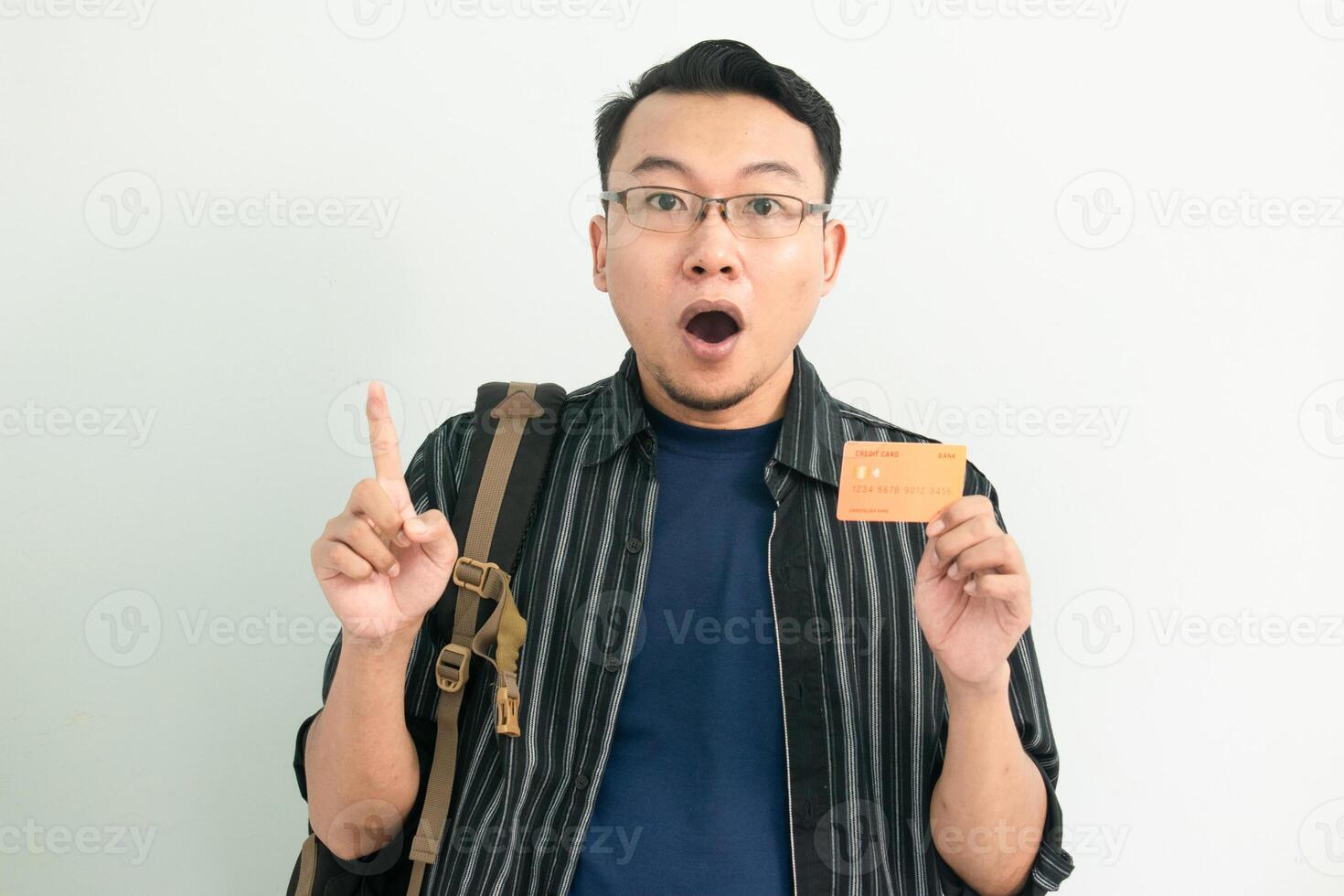 Surprised asian student hold credit card with pointing gesture. Banking, Financial isolated concept. photo