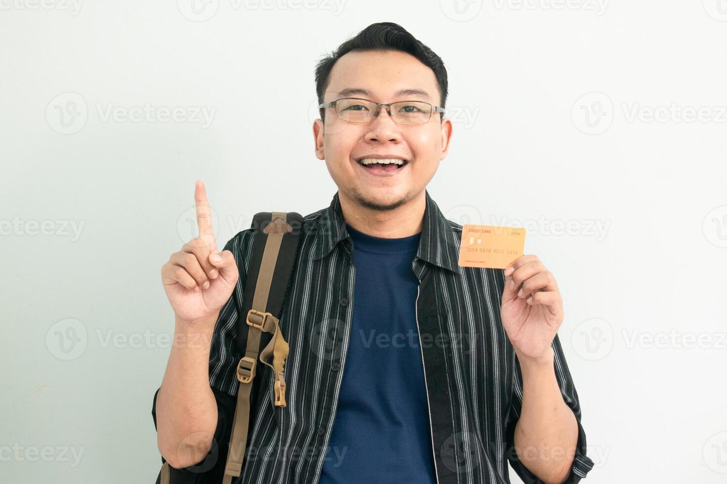 Delighted asian student hold credit card with pointing gesture. Banking, Financial isolated concept. photo