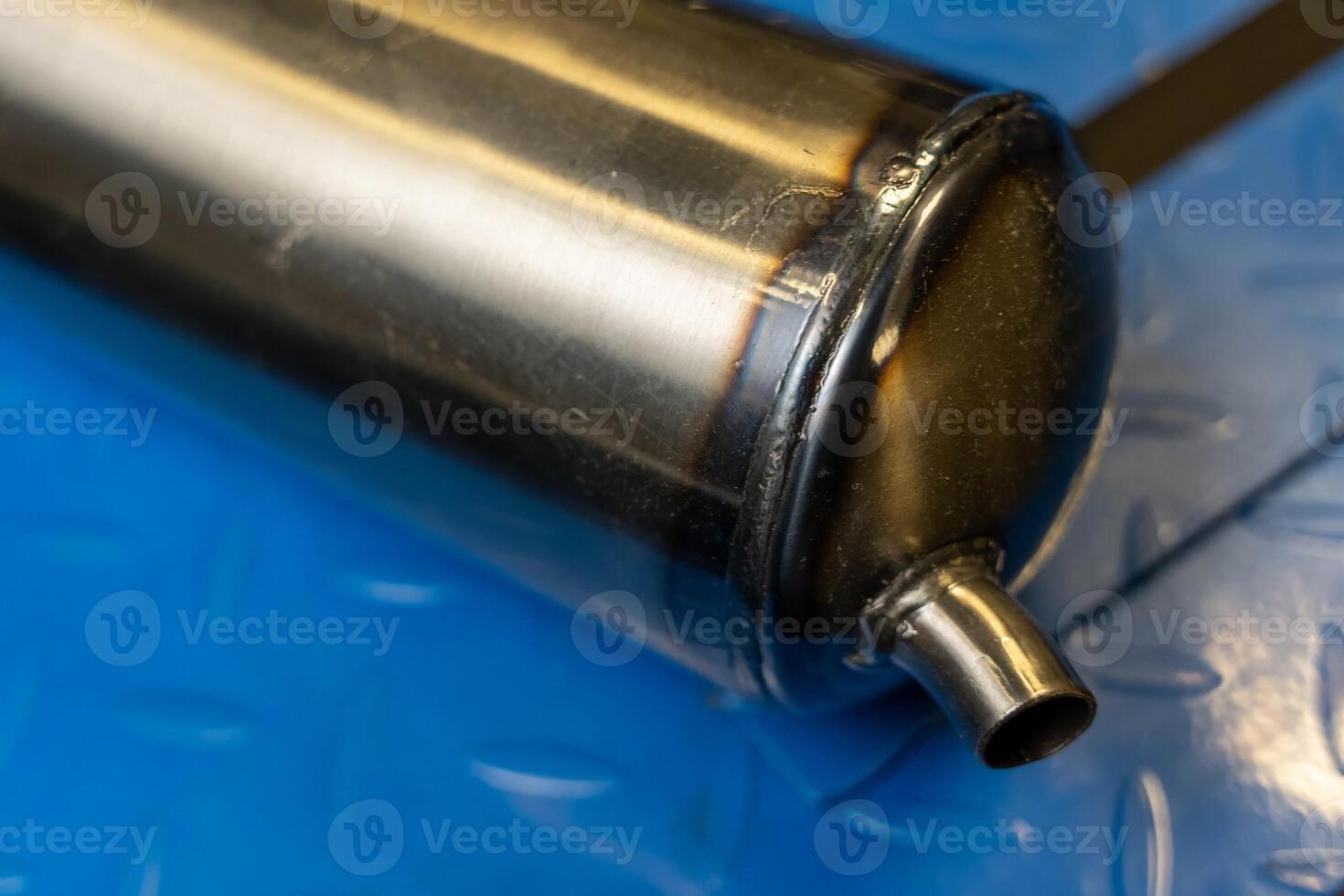 Welded metal cylinder resting on blue metal surface photo