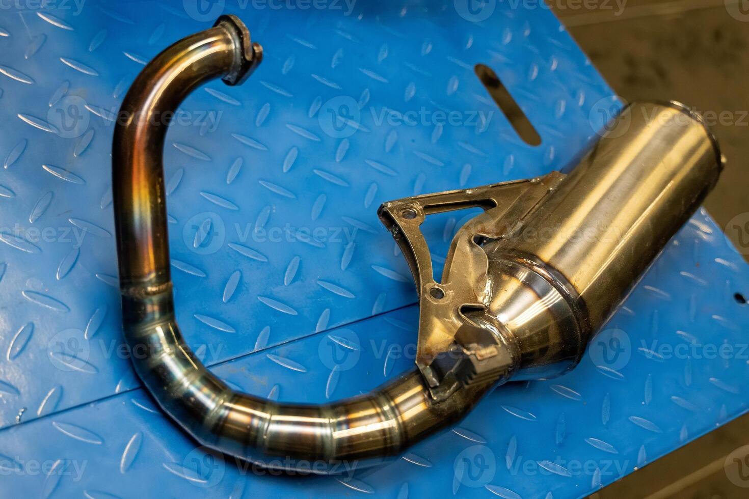 Motorcycle exhaust pipe resting on blue metal surface photo