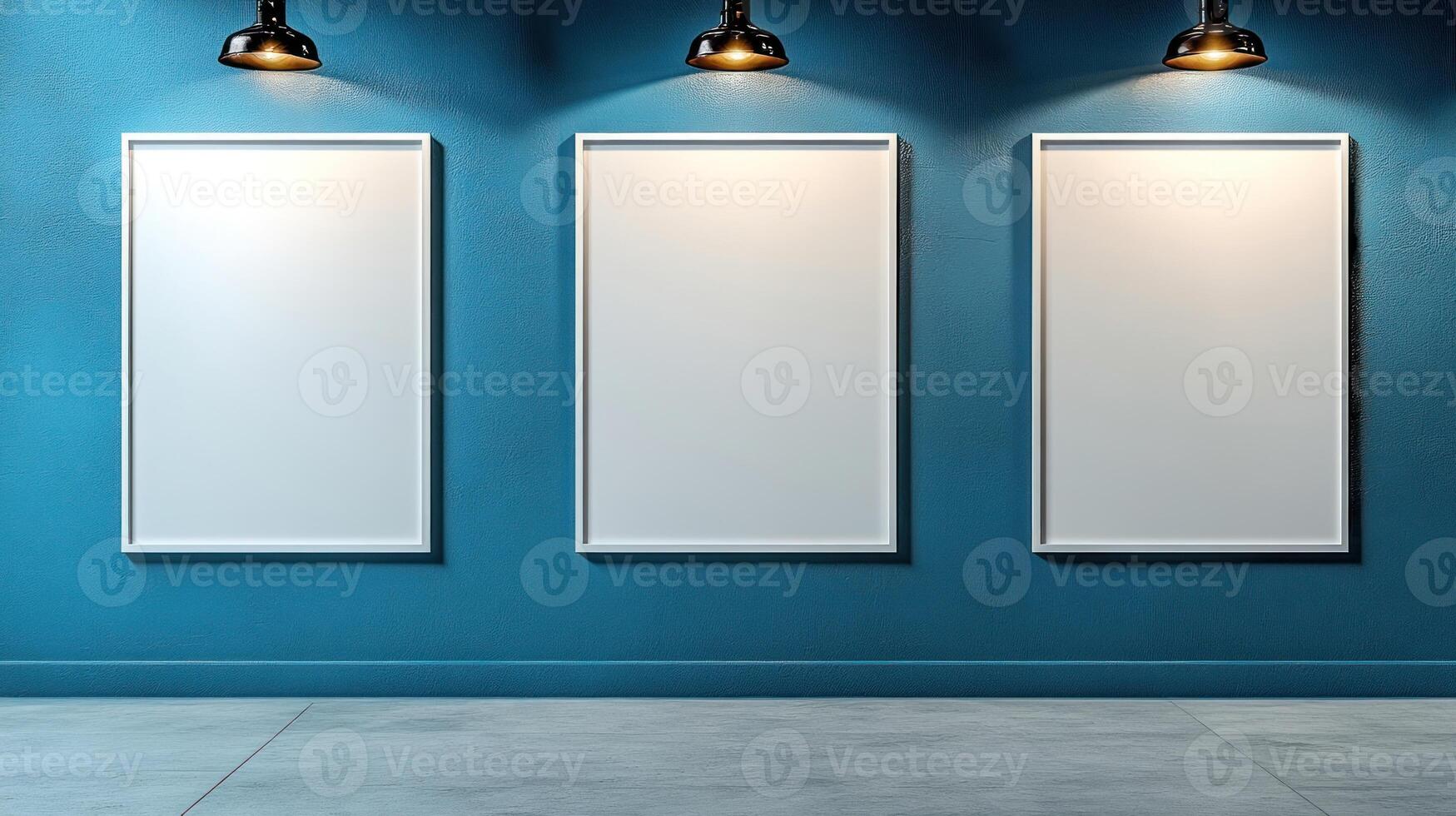 Three blank frames hang on a deep blue wall, illuminated by industrial-style lamps photo