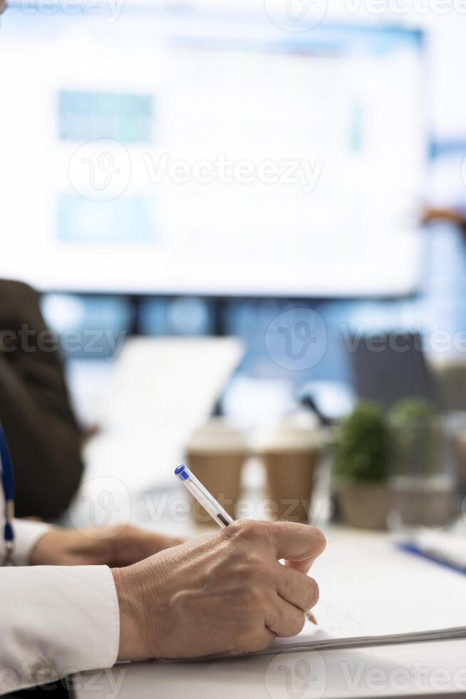 Financial consultant takes notes during a project briefing meeting, working on allocating available resources to meet the business objectives. Expert making future projections. Close up. photo