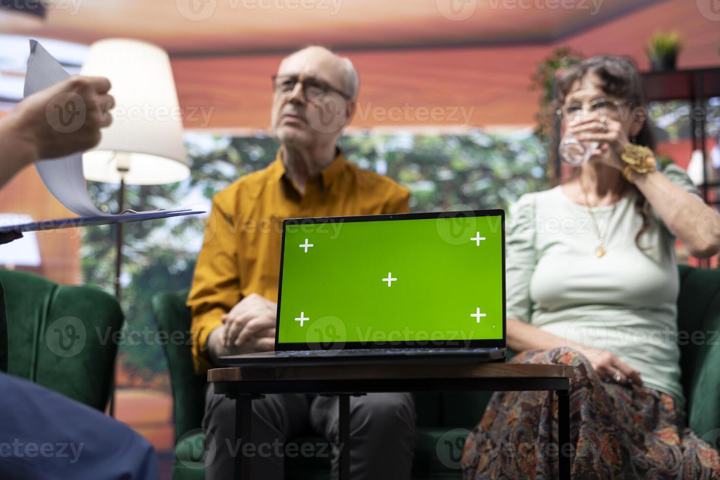 Caregiver nurse consulting senior couple next to chroma key mockup display on laptop, discussing about medical treatment and prescription. Specialist offering support and assistance. photo