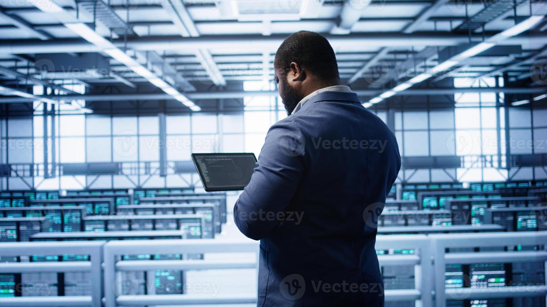 Computer scientist in data center running error checking utilities on tablet to fix bugs. IT expert in server hub facility looking for network issues affecting supercomputers performance, camera B photo