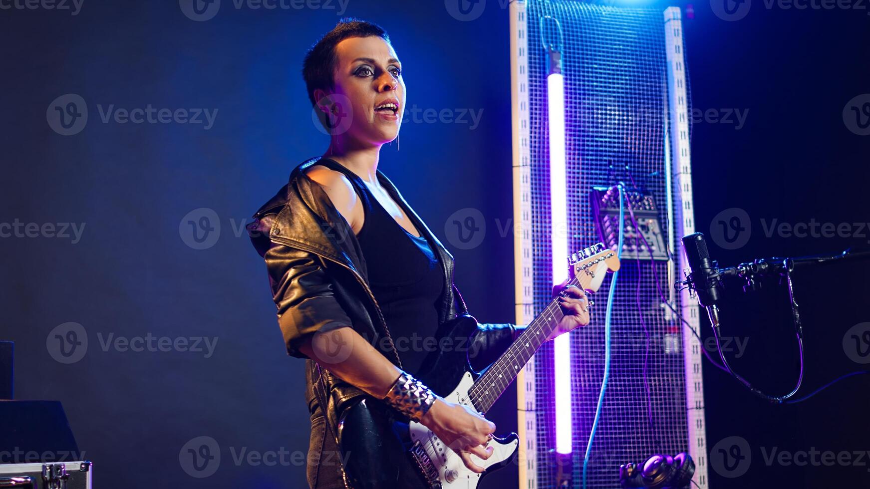 Displeased woman giving a dislike while she performs live in concert, expressing her disagreement with a thumbs down in studio. Dissatisfied female rocker with a cool edgy vibe. Camera A. photo