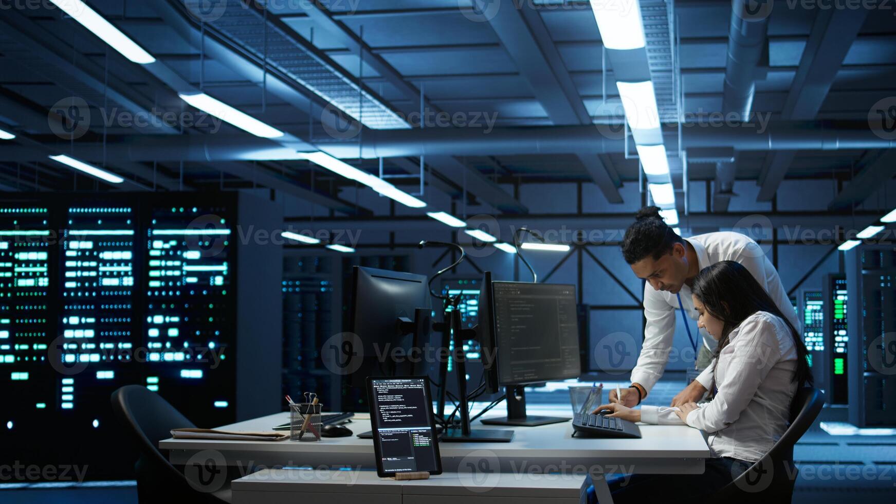 Teamworking colleagues in high tech data center managing and maintaining databases, ensuring data integrity, security and availability. Team of specialists updating server room systems, camera B photo