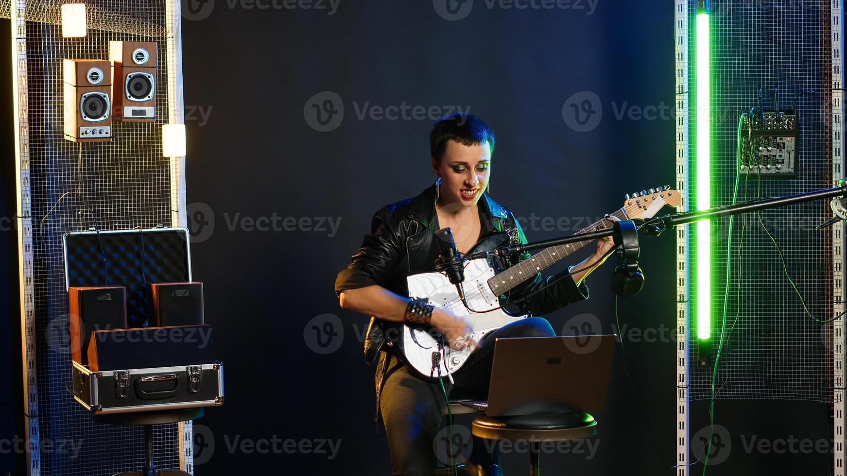 Female musical artist feeling frustrated at practice session in rehearsal room, trying to perfect her vocals for a live performance with alternative music. Studio vocal training with guitar. Camera B. photo