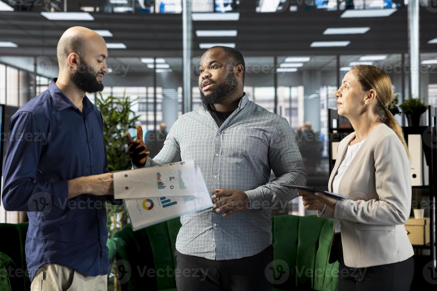 African american businessman talking with coworker in startup company, looking at financial business documents. Arab man in office checking accounting figures with colleague photo
