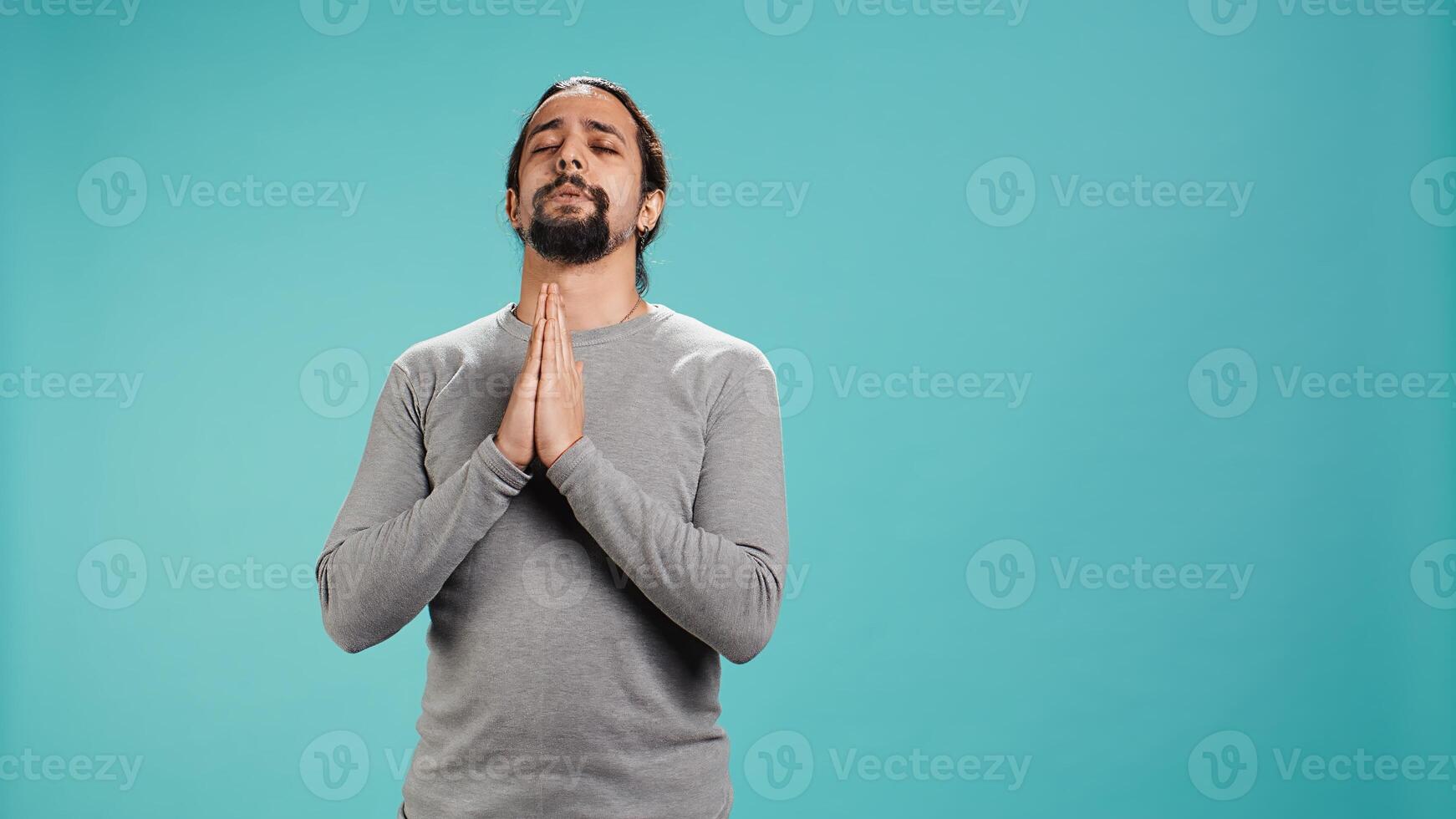 Pious man praying to his god, asking for forgiveness. Spiritual person doing worship hand gesturing, confessing, begging for pardon, isolated over studio background, camera B photo