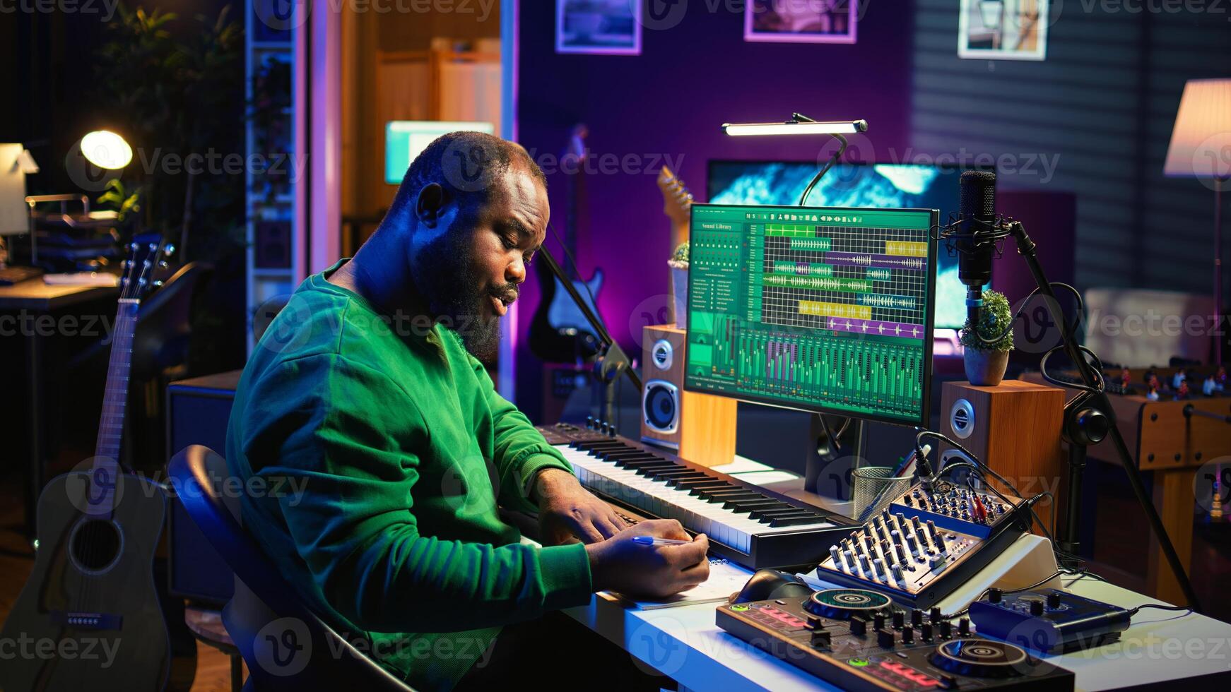 Talented artist composing new lyrics for his tracks and recording music with audio devices in his home studio. Singer composer writes melodic material by taking notes and creating rhymes or songs. Camera B. photo