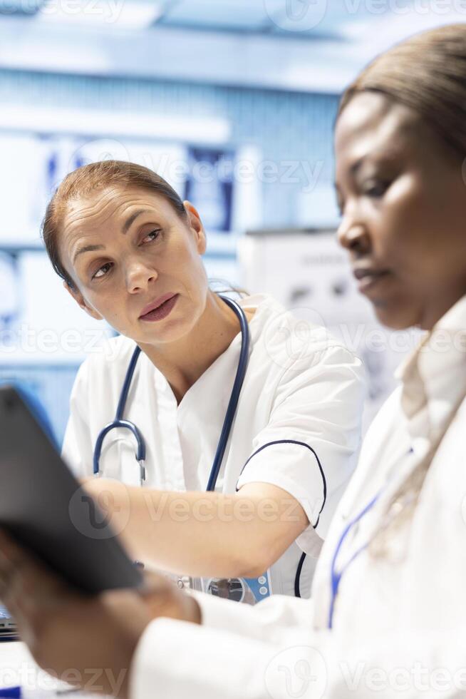 Healthcare professionals staff gather in a clinic to analyze x ray data, meeting to examine radiography scans and hospital records. Licensed experts collaborate on treatment plans, teamwork. photo