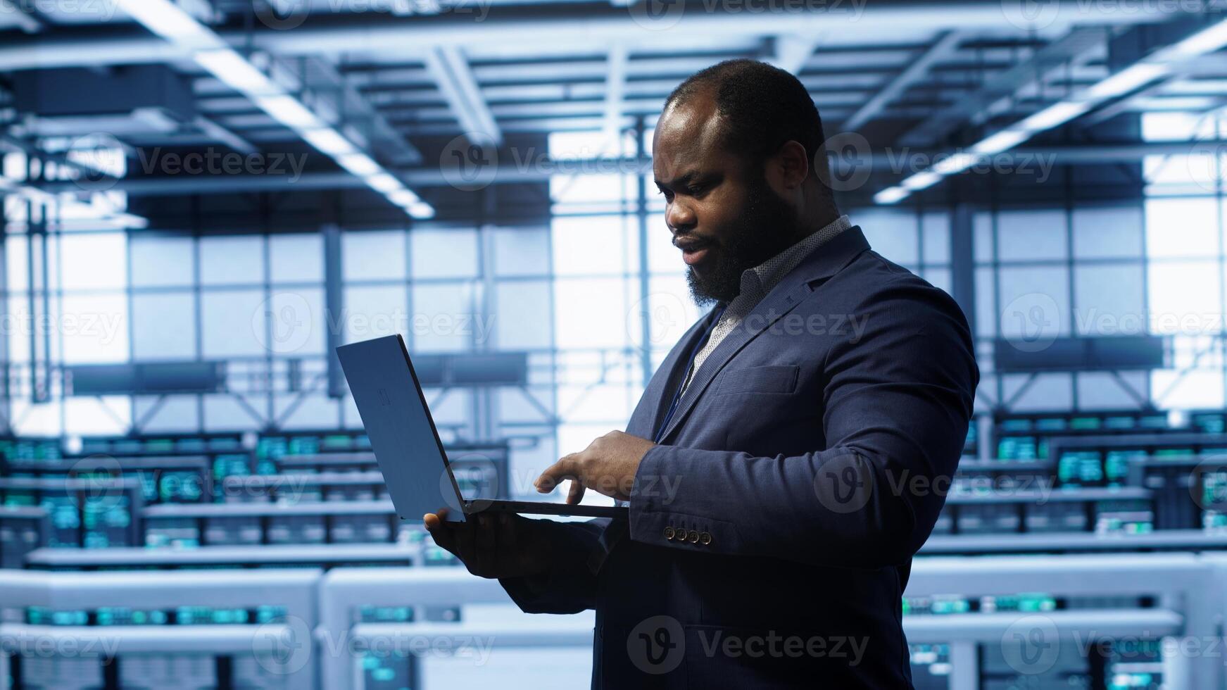 Computer scientist in server hub checking recovery plan on laptop, monitoring hardware energy consumption. IT specialist uses notebook in data center facility, ensuring rigs are functioning, camera A photo