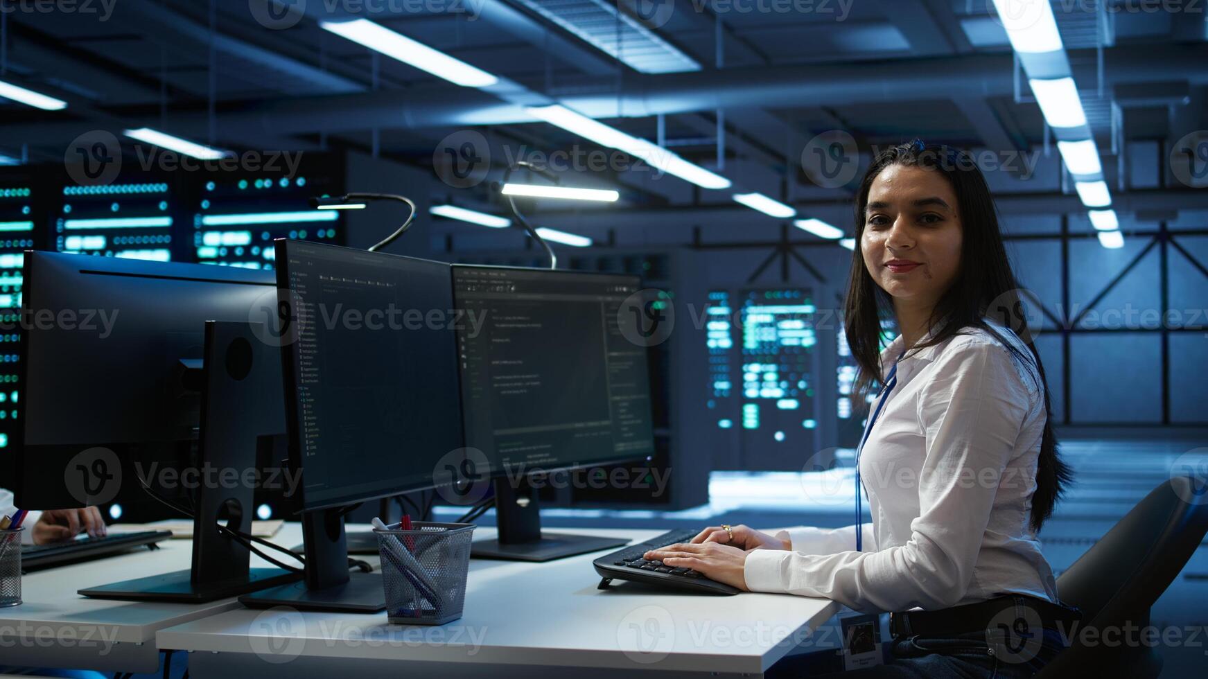 Portrait of smiling engineer overseeing data center, making improvements and updates to ensure system can handle networking tasks. Upbeat server room worker tracking network traffic, camera B photo