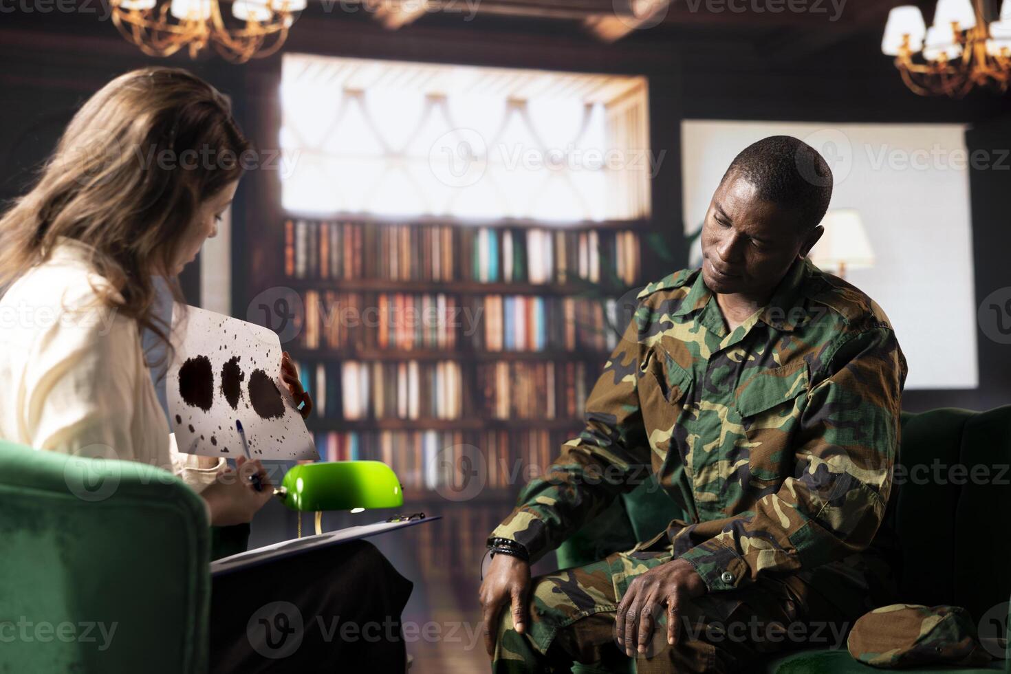 African american soldier in military uniform sits with a therapist, viewing a Rorschach test illustration to share feelings and discuss trauma. PTSD and shell shock counseling session. photo