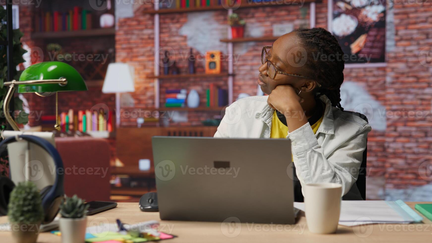 Fatigued teleworker feeling overworked, taking break after working too much on job tasks. Exhausted woman at home pausing work to relax and regain energy, looking out the window, camera B photo