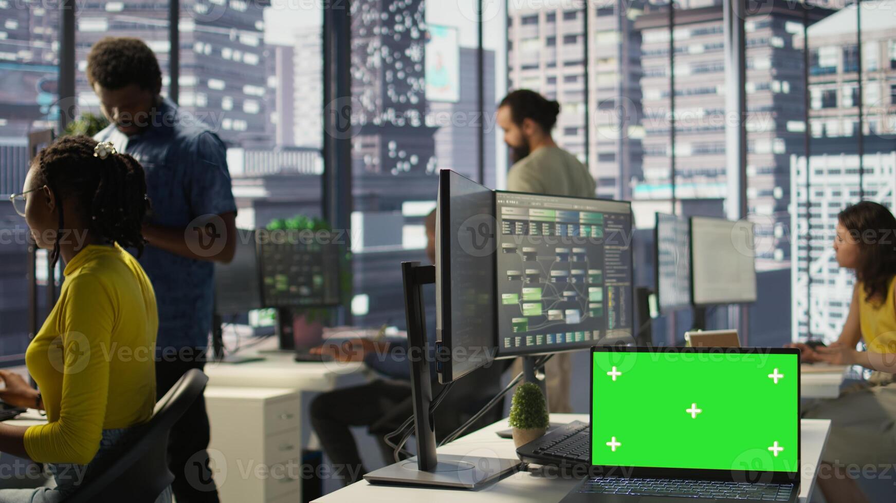 Green screen laptop on desk in workspace with admins in background doing software quality assurance. Chroma key notebook in office with woman at work inspecting coding on device, camera B photo