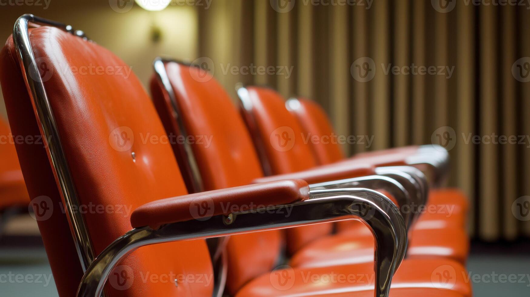 Row of red theater chairs with chrome armrests in auditorium setting photo