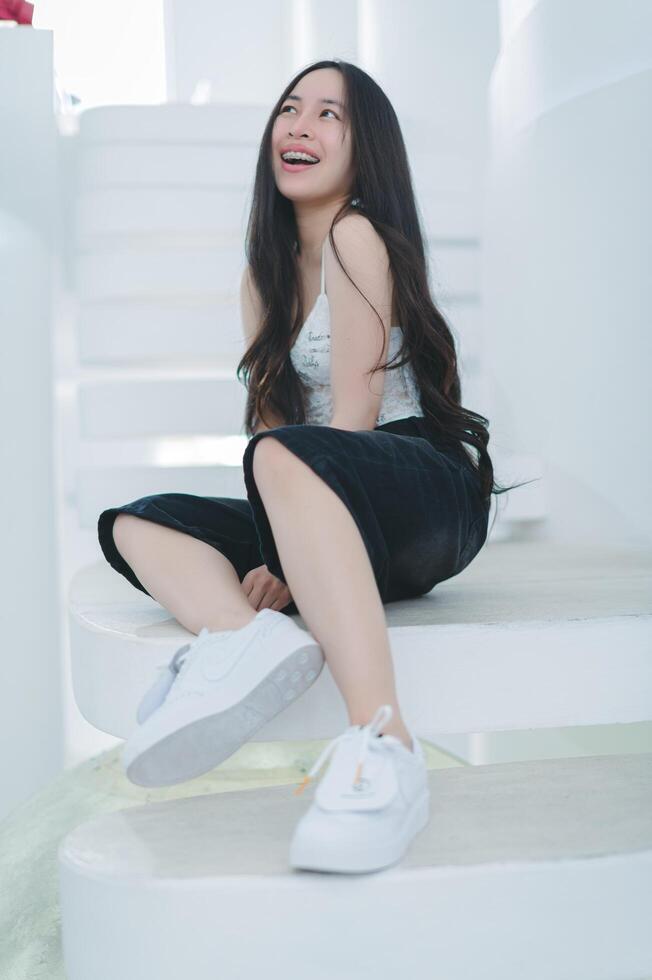Young Woman Smiling on White Steps Wearing Casual Outfit and Sneakers photo